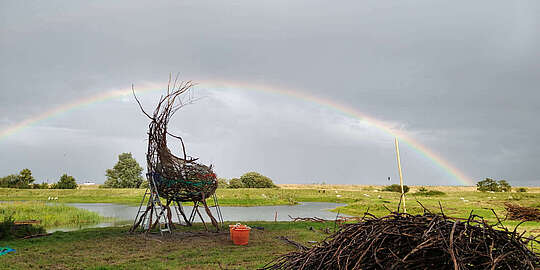 Kunstwerk im Marschland vor einem Regenbogen