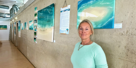 Eine Frau steht vor einer Bilderausstellung an einer Wand
